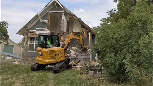 A bulldozer digging through a house that has been demolished